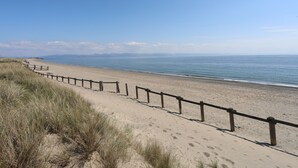 Uma praia de areia com uma cerca de madeira ao longo da orla.
