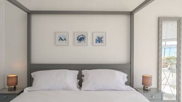 A bedroom with a bed, two bedside tables, and three framed artworks on the wall.