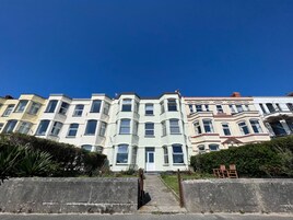 Una hilera de edificios de varios pisos con balcones salientes y un cielo azul despejado.