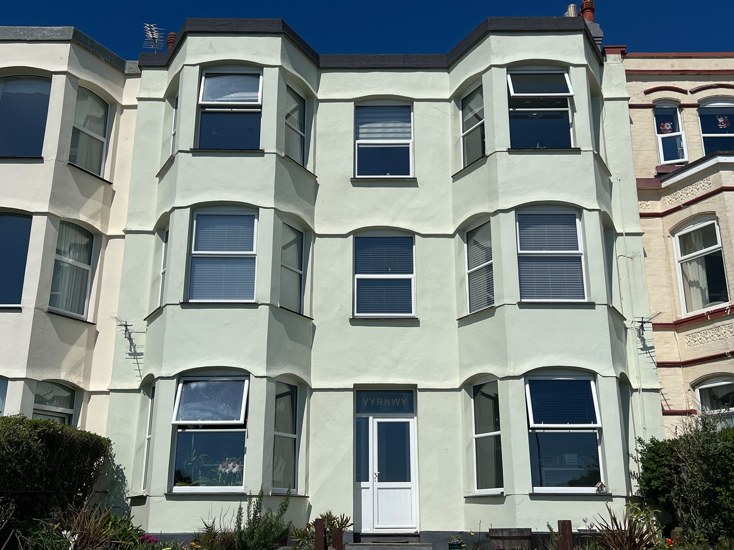 A multi-story building with bay windows and a white facade.