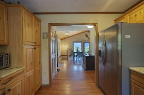 A kitchen with wooden cabinets, a stainless steel refrigerator, and a dining area with a table and chairs. - Misty Morning, Sleeps 8, Amazing Grandfather View, (Blowing Rock)