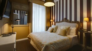 A hotel room with a large bed, two bedside lamps, a desk with a lamp, a TV, and a mirror. - The B Place Ezio (Rome)