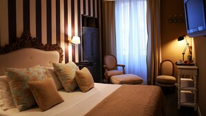A hotel room with a large bed, a chair, a desk with a lamp, and a television. - The B Place Ezio (Rome)