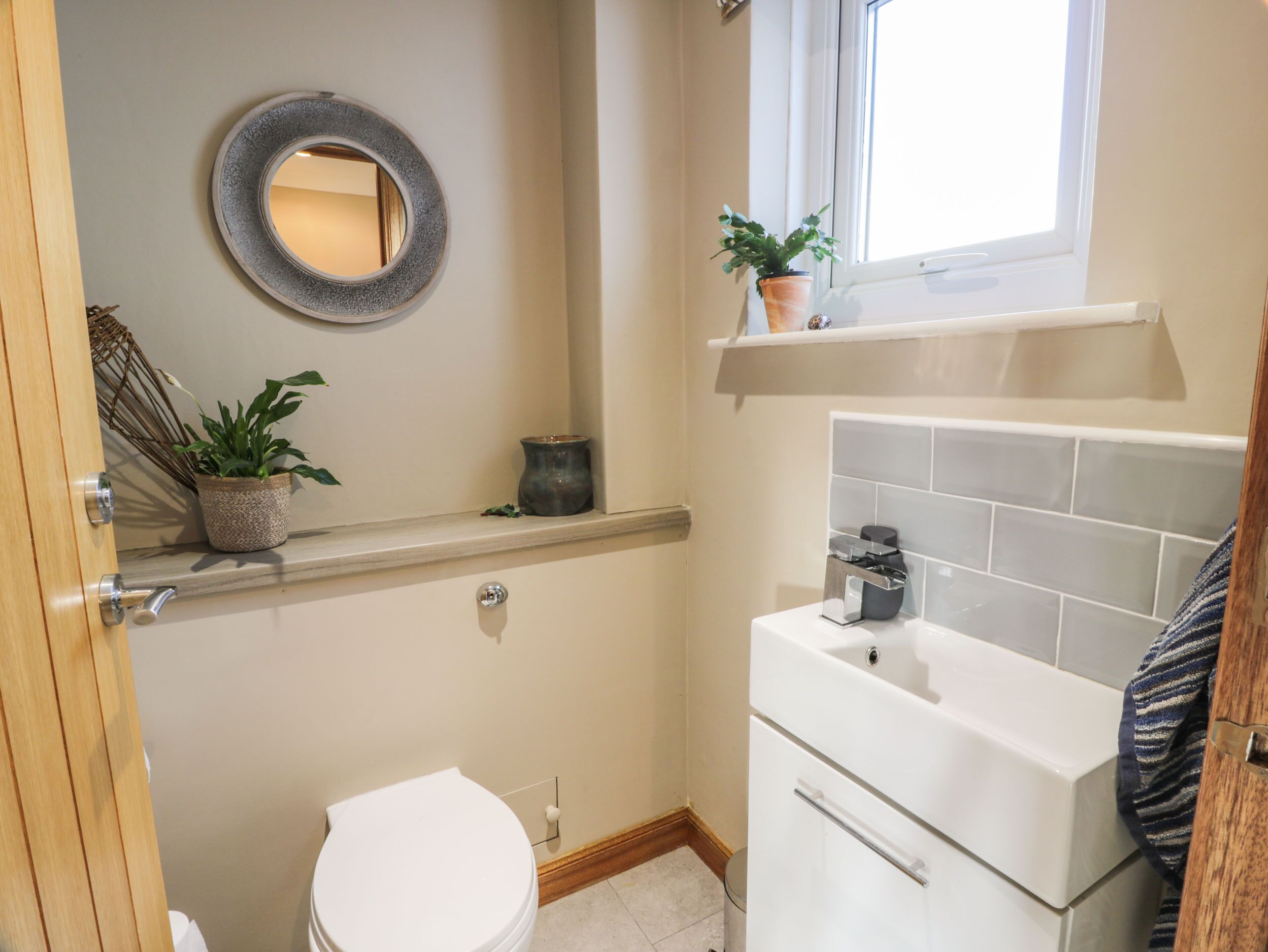 Un baño con inodoro, lavamanos, espejo y ventana.