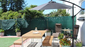 A patio with a table, chairs, a bench, and a large umbrella. - Millbrook Cottage (Dalbeattie)
