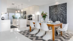 Un comedor moderno con una mesa de madera, sillas blancas y un tapete con estampado geométrico.