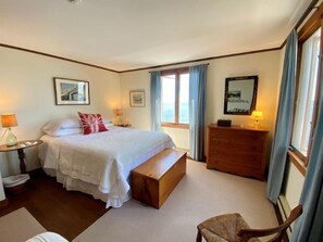 Relax in this inviting room featuring a large bed, wooden bench, and dresser, with ample space for a comfortable stay.
