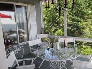 Relax in a serene outdoor space with a glass-top table and comfortable seating, surrounded by lush greenery.