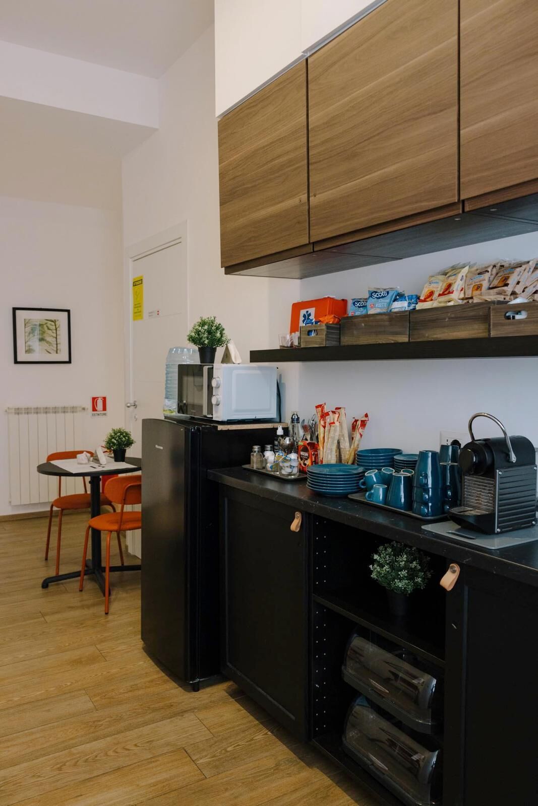 A compact kitchenette with a refrigerator, microwave, and a small dining area with chairs and a table.