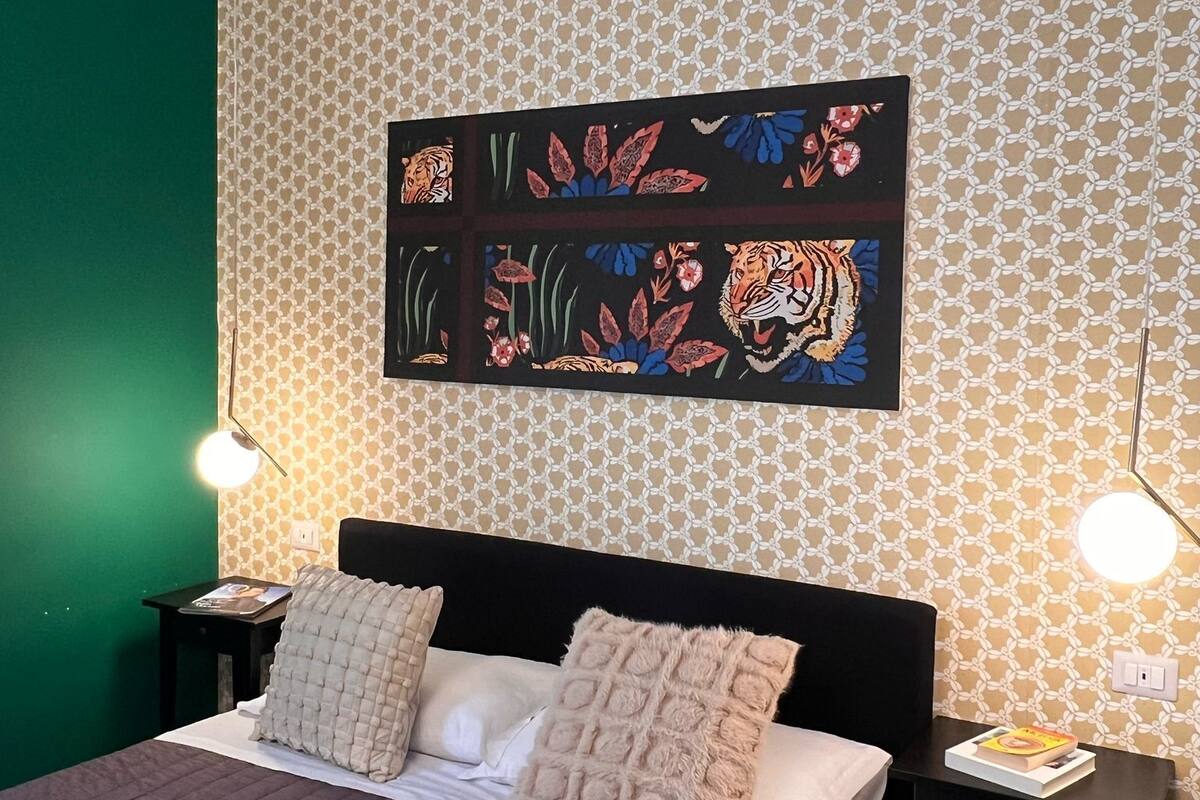 A bedroom with a bed, two bedside tables, and a wall with a geometric pattern.