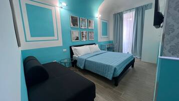 A bedroom with a bed, a sofa, a desk, and a TV.