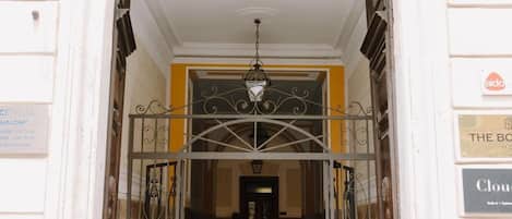 An arched entrance with a metal gate, a chandelier, and a tiled floor.