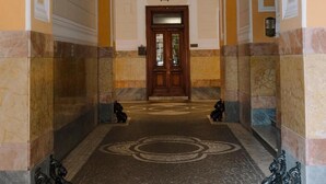 Un pasillo con piso estampado, una puerta de madera al final y una lámpara colgante.