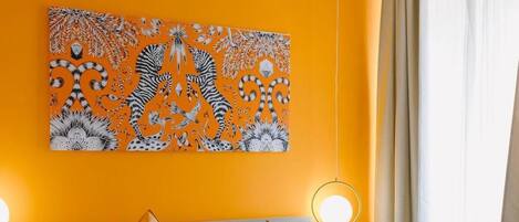 Une chambre d’hôtel avec un grand lit, deux tables de chevet, une œuvre d’art accrochée au mur et une fenêtre avec des rideaux.