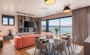 A modern living room with a dining area, a flat-screen TV, and a view of the sea. - Villa Ponti ZadarVillas (Novigrad)