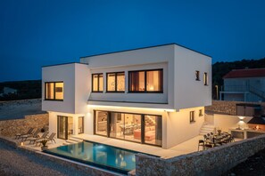 A modern two-story house with a swimming pool, outdoor seating, and a stone wall surrounding the property. - Villa Ponti ZadarVillas (Novigrad)