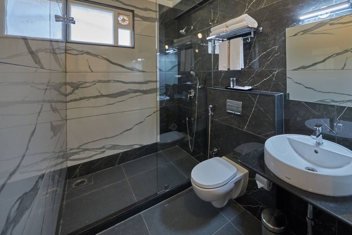A modern bathroom with a glass shower enclosure, a toilet, a sink, and a vanity.