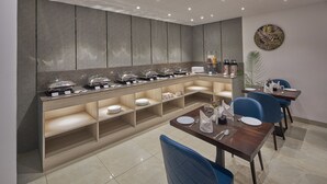 Un espace repas moderne, aménagé avec un buffet proposant différents postes de service et diverses options de sièges.