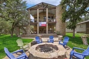 A two-story stone building with a balcony, outdoor seating area with chairs, and a flag. - Heaven In Hells Gate! Water access,kayaks,game rm! (Strawn)