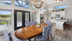 A spacious kitchen with white cabinets, a large island, and a dining area with a wooden table and patterned chairs.