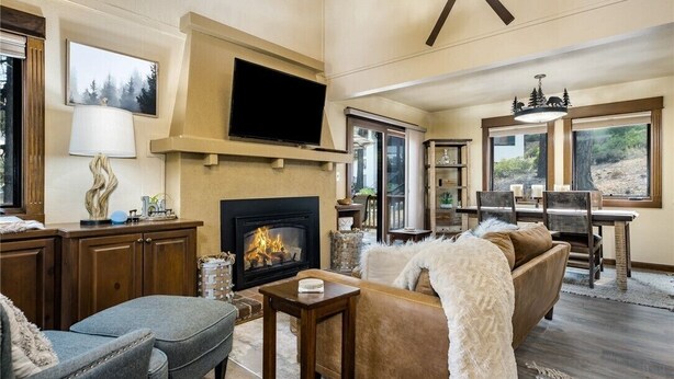 Una sala de estar acogedora con chimenea, televisión y comedor con vistas al exterior.
