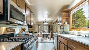 Una cocina con armarios de madera, electrodomésticos de acero inoxidable y una ventana con vistas al follaje.
