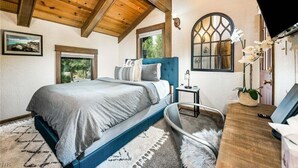 Un dormitorio con una cama, una mesita de noche, un escritorio, una silla y una ventana.