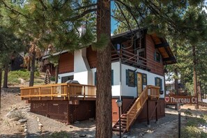 Guests can enjoy a cabin-style retreat with a wooden deck and staircase leading to the main entrance.