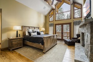 Une chambre spacieuse avec un grand lit, une tête de lit en bois et une cheminée en pierre.
