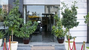 The entrance of Tamrah Hotel with potted plants and red ropes. - Tamrah Suites Hotel (Amman)