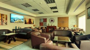 A spacious living room with multiple seating areas, a fireplace, and artwork on the walls. - Tamrah Suites Hotel (Amman)