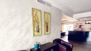 A lobby with a marble wall, two framed artworks, a reception desk, and leather seating. - Tamrah Suites Hotel (Amman)