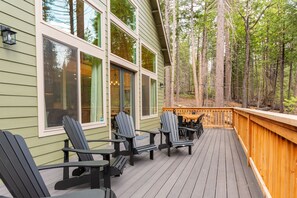 Una terraza de madera con sillas Adirondack y barandilla de madera.