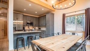 Una cocina moderna con armarios grises, una isla de madera y una amplia mesa de comedor.