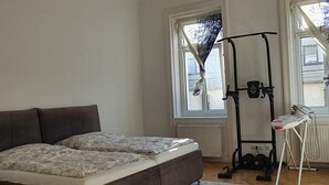 A bedroom with a bed, exercise equipment, and two windows. - Servicierte Wohnung in der City (Vienna)