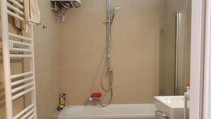 A bathroom with a shower, a bathtub, a white sink, and a towel rack. - Servicierte Wohnung in der City (Vienna)