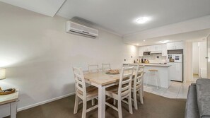 Une cuisine de taille réduite avec des meubles blancs, un four à micro-ondes et un réfrigérateur.