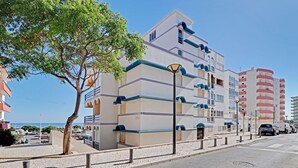 Ett hotell med flera våningar, balkonger, en asfalterad gata och en klar himmel.