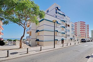 A multi-story hotel with balconies, a paved street, and a clear sky. - Monte Gordo Beach I by Homing (Vila Real Santo Antonio)