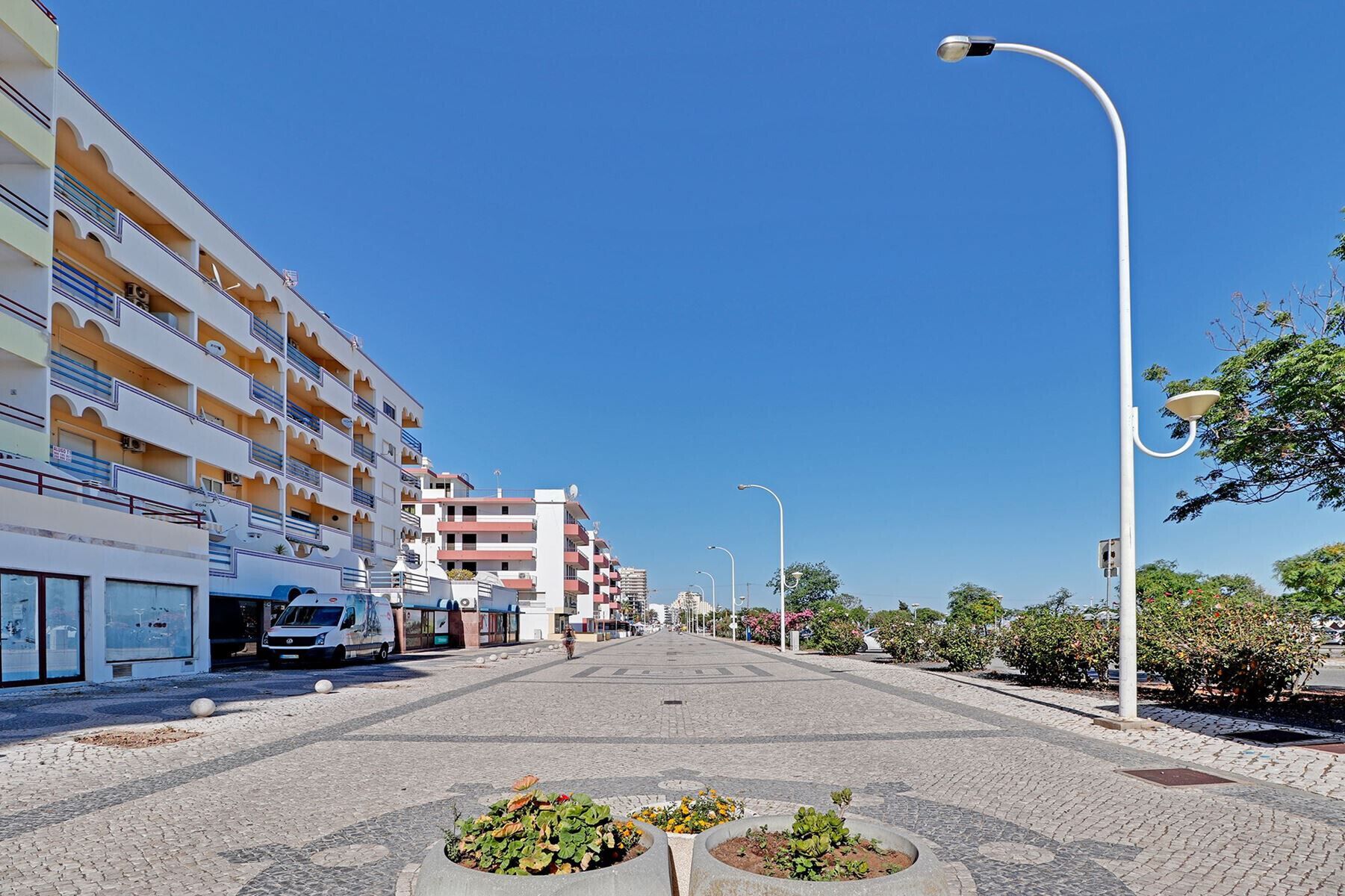 Un hotel de varios pisos con balcones, una calle pavimentada y farolas.