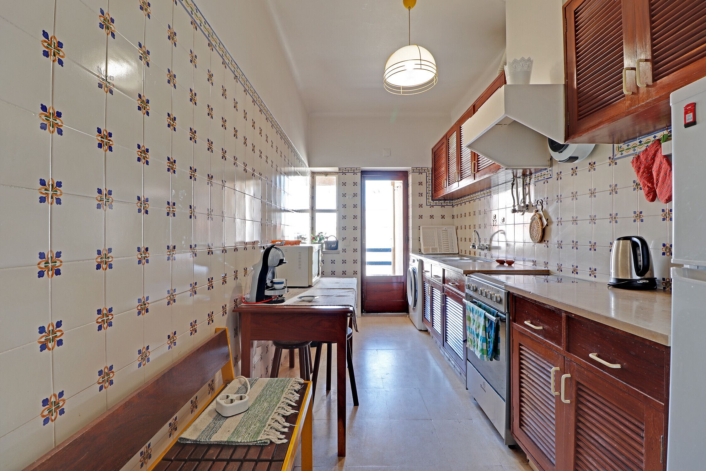 Una cucina con piastrelle decorate, mobili in legno e un'area pranzo con tavolo e sedie.