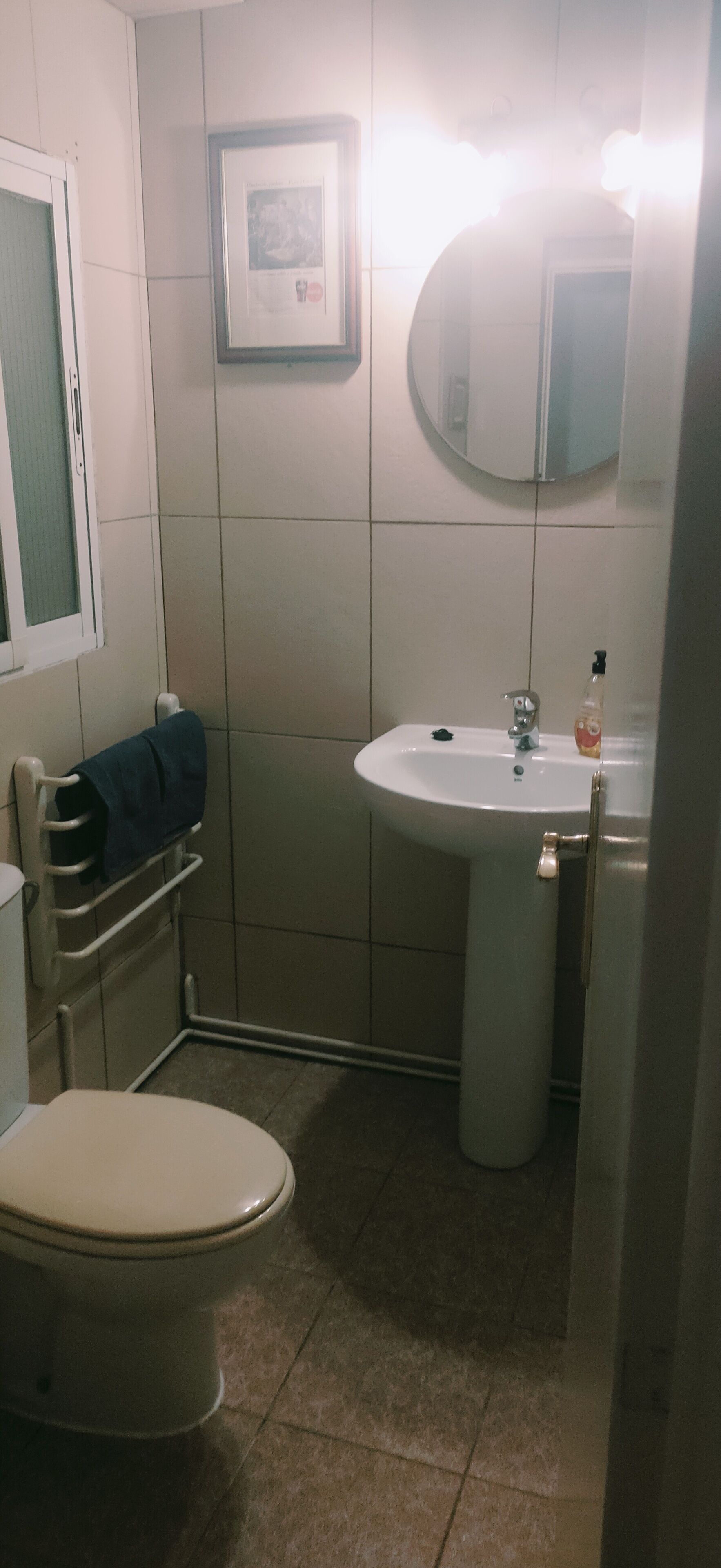 Une petite salle de bain avec des toilettes, un lavabo et un miroir.