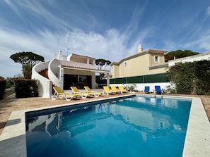 A swimming pool with lounge chairs, a covered patio, and a two-story building with a tiled roof. - Vilamoura Ocean Villa With Pool (Loulé)