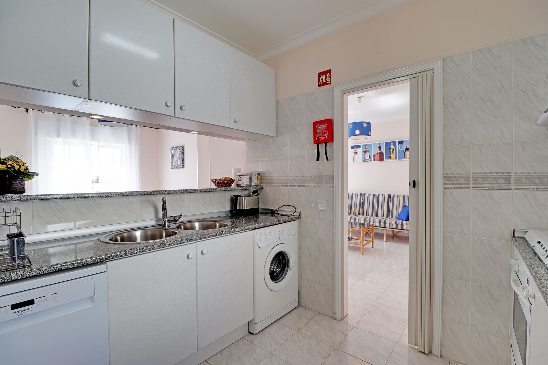 A modern kitchen with white cabinets, a built-in washing machine, and a double sink.