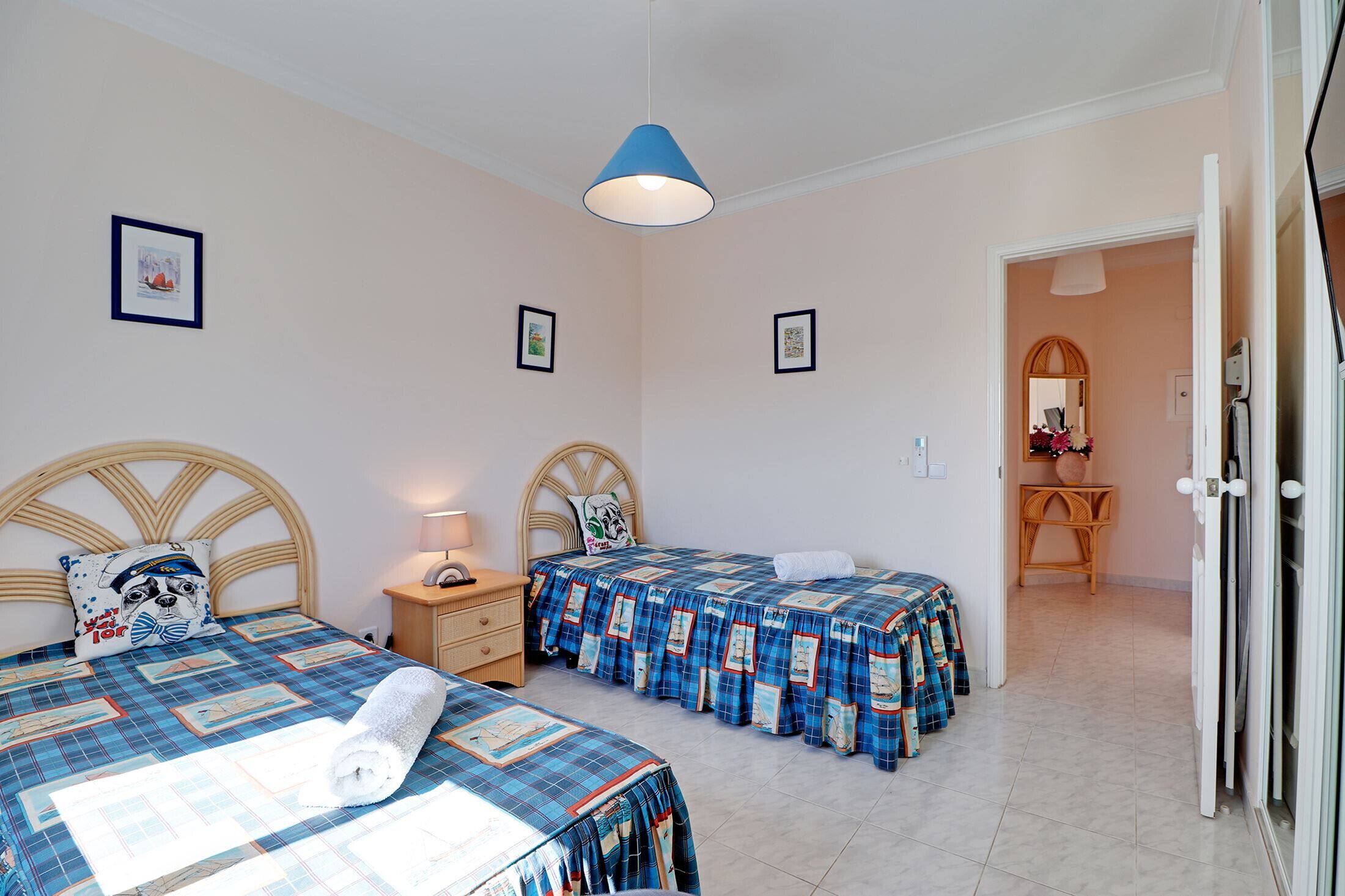 Un dormitorio con dos camas, una mesita de noche, una lámpara y una puerta que da a un baño.