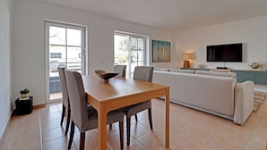 A modern living room with a dining table, sofa, and TV. - Tavira Formosa BAY 1 by Homing (Tavira)