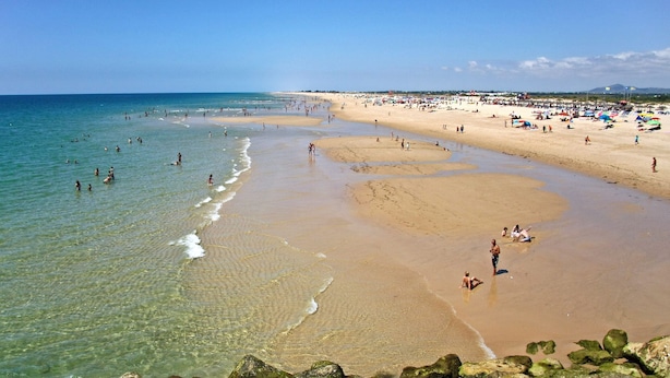 A beach with clear water, sandy shore, and rocks in the foreground. - Tavira Formosa BAY 1 by Homing (Tavira)