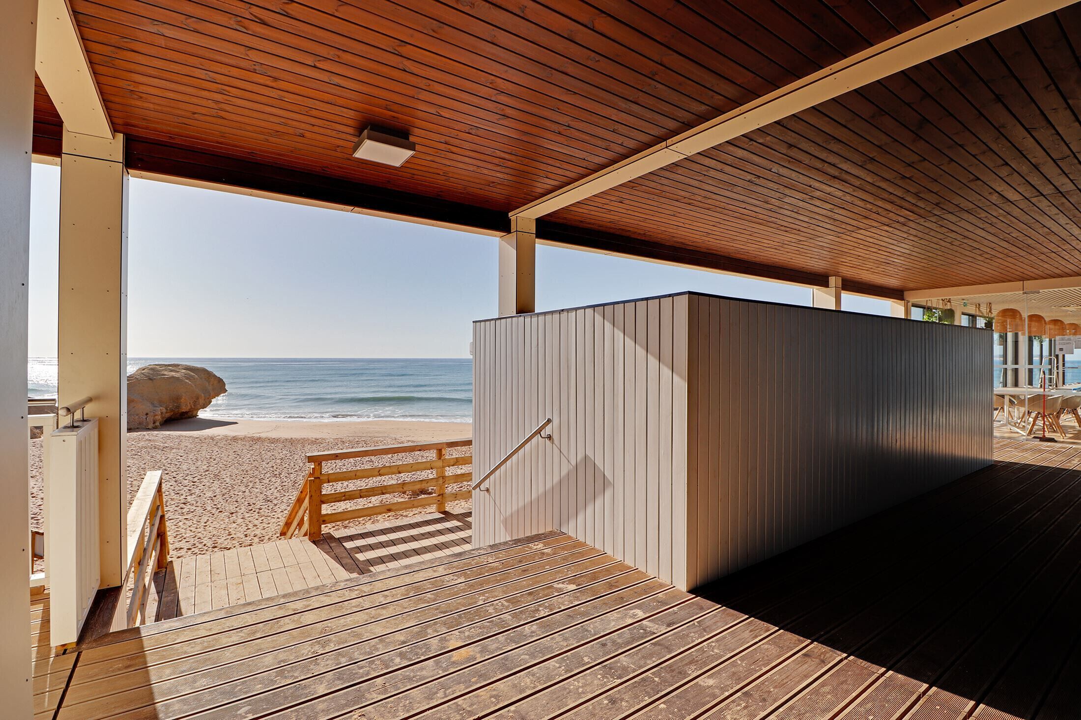 Una terraza de madera que da a una playa con vista al océano.