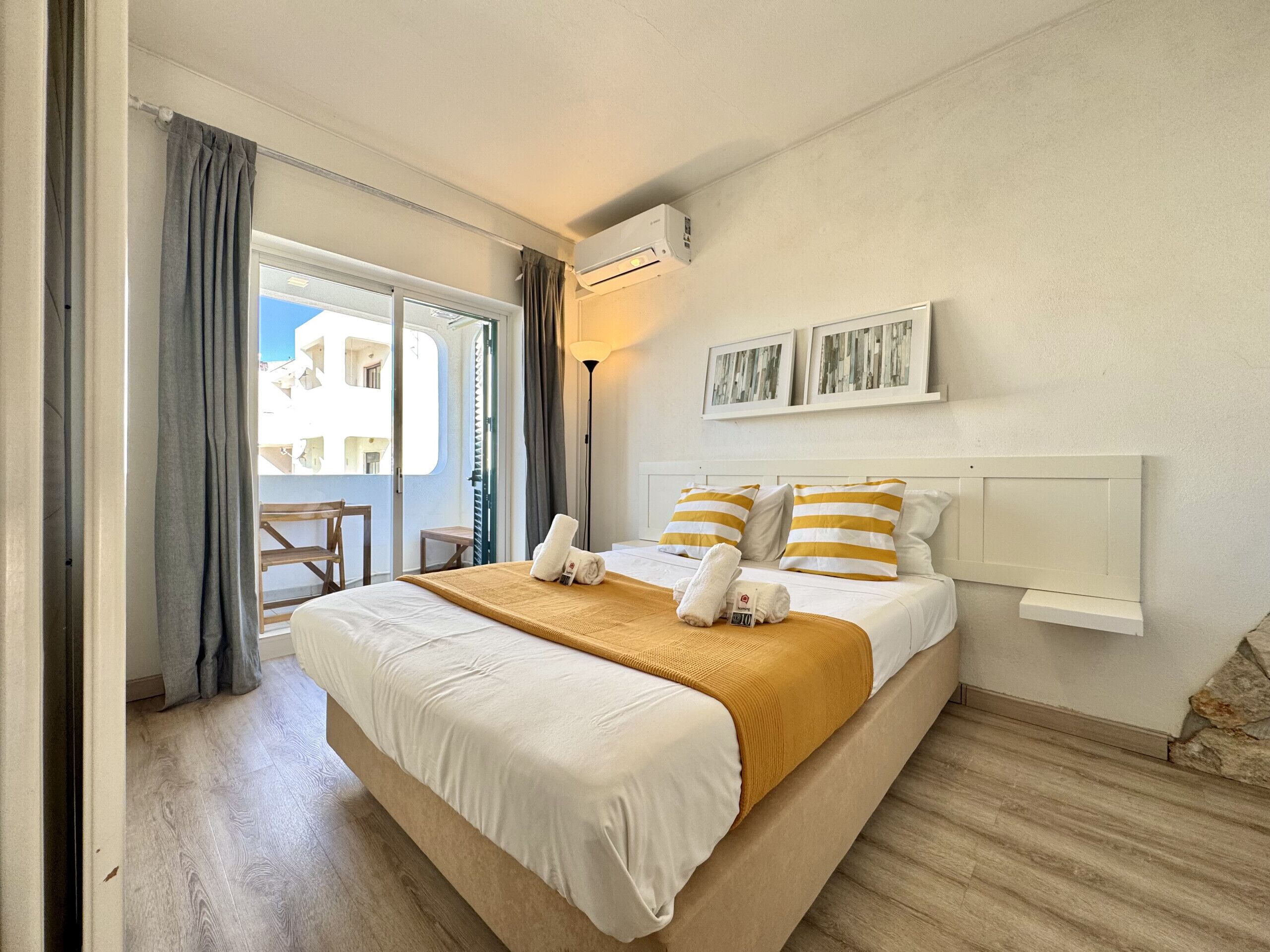 A hotel room with a bed, a balcony, and a view of buildings.