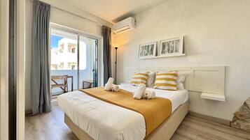 A hotel room with a bed, a balcony, and a view of buildings.